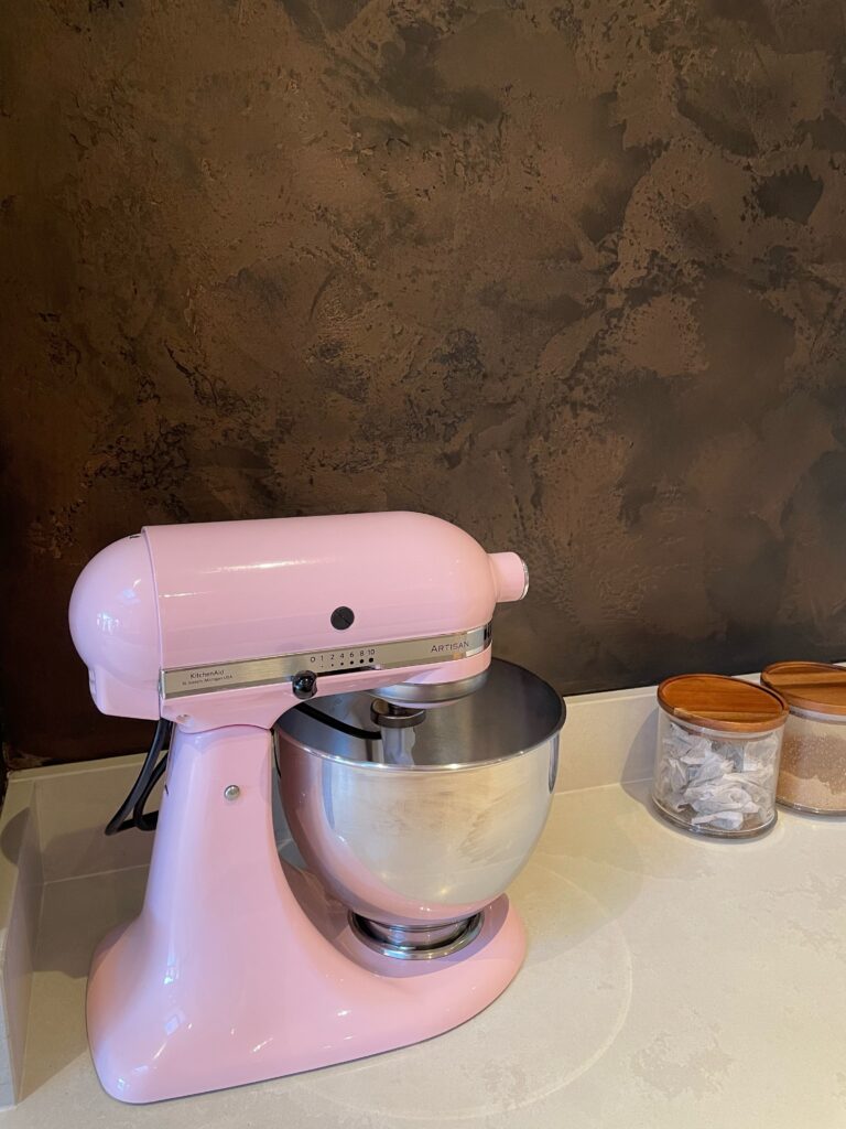 Black and bronze textured venetian plaster feature wall close up with contrasting pink mixing bowl in London